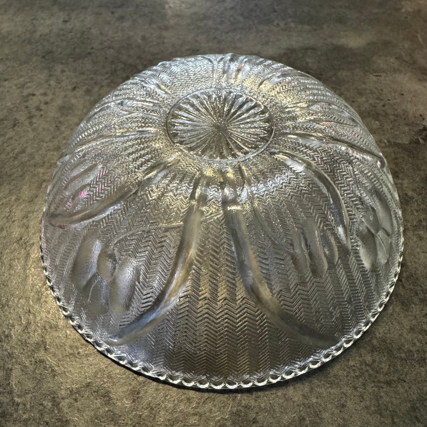 Clear glass cake stand with intricate patterns on a textured surface