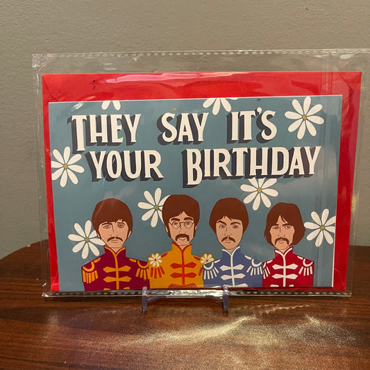 Birthday card with Beatles illustration and text 'They say it's your birthday' on a clear stand.