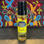 Perfume oil bottle labeled 'Vanilla' by 'Moonlight Rose' on a textured surface with a colorful embroidered fabric background.