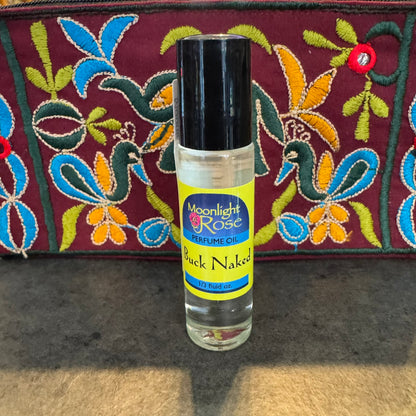 Perfume oil bottle labeled 'Moonlight Rose' with colorful embroidered fabric in the background