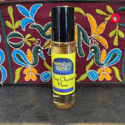 Perfume oil bottle labeled 'Nag Champa Flora' with a colorful embroidered background